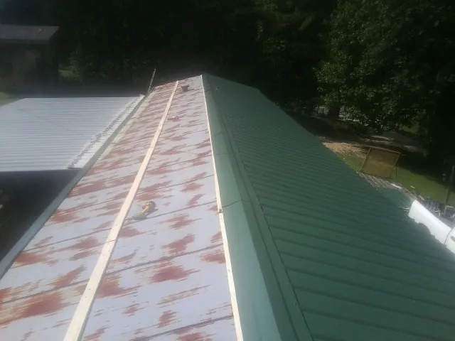 Old rusted panels beside newly installed green metal roofing — Wind Damage Roof Repair by Roofing Brothers in Hennepin