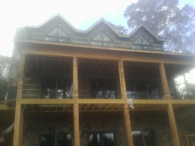 Dormers and porch framing on a large log home under construction — Roof Coating work by our crew in Hennepin
