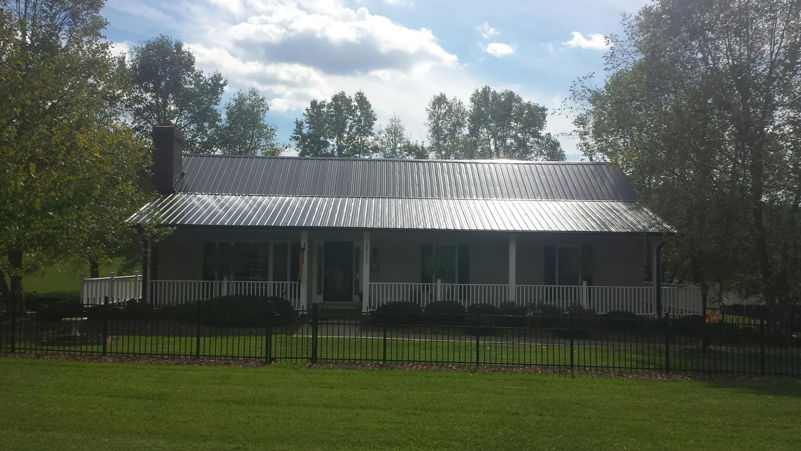 Gray metal roof on a brick ranch with a full width front porch — Gutter Guard Installation work by our crew in Hennepin