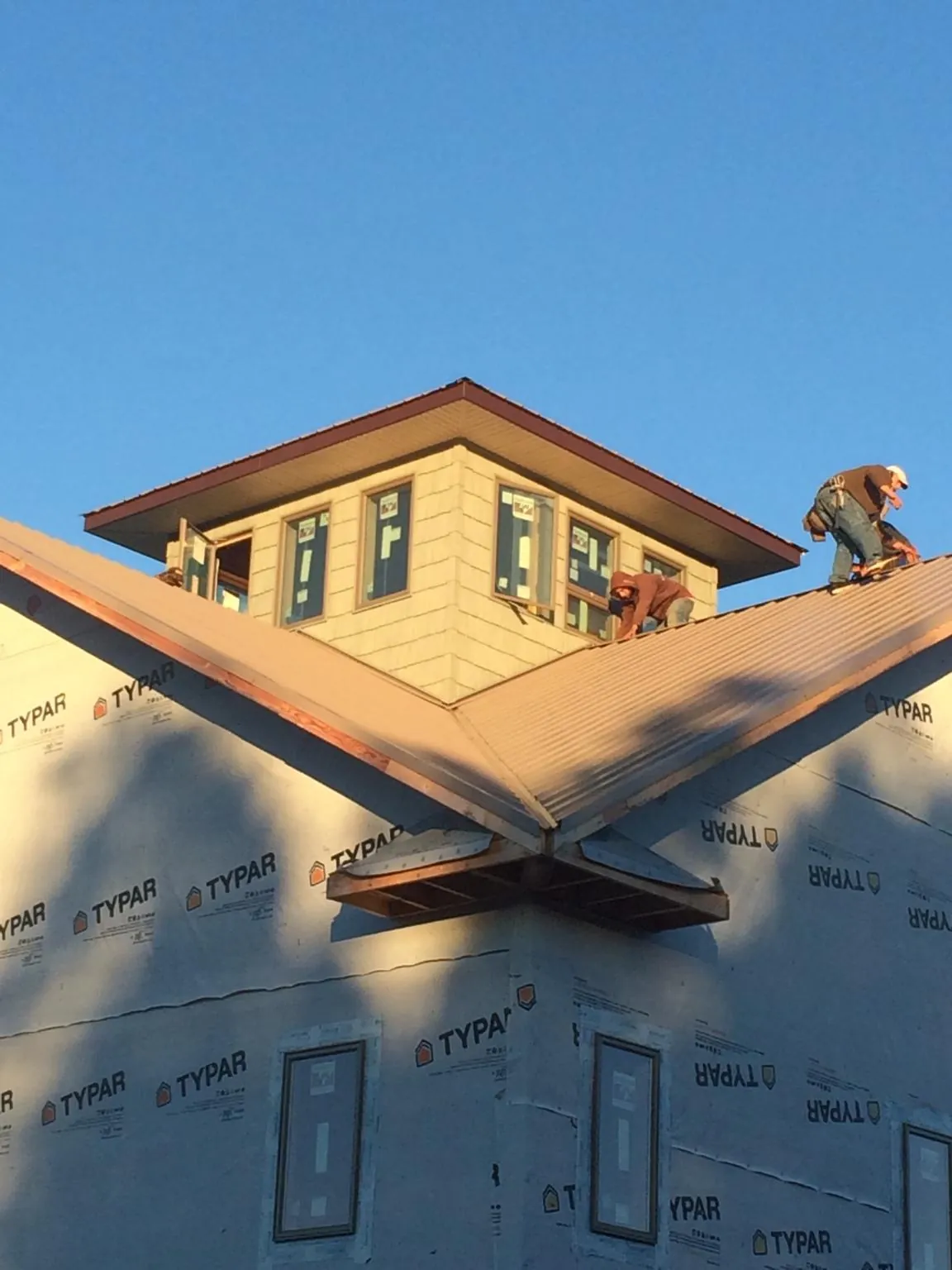 Roofers working around a rooftop cupola on a new metal roof at sunset — Roof Waterproofing in Hennepin by Roofing Brothers